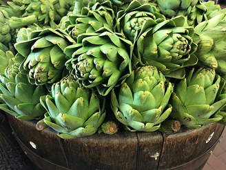 A large container holding many green artichokes.